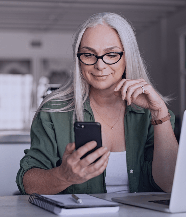 Person checking their mobile phone at a desk.
